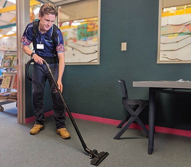 Person vacuuming the floor in a schoole